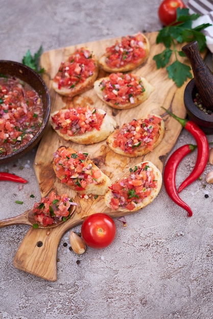 Tasty salsa bruschetta snacks at domestic kitchen on wooden cutting board