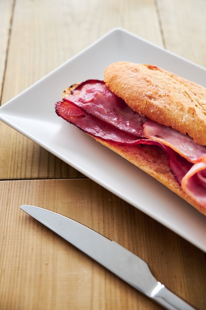 Tasty sandwich made of crispy baguette and bacon