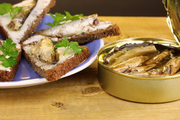 Фотография вкусные бутерброды со шпротами на тарелке на деревянном столе на коричневом фоне