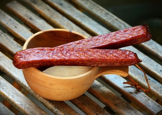 Tasty sausages on a wooden cup background