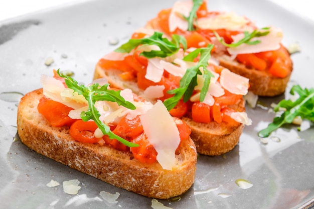 Tasty savory Italian appetizers, or bruschetta, on slices of toasted baguette garnished with basil