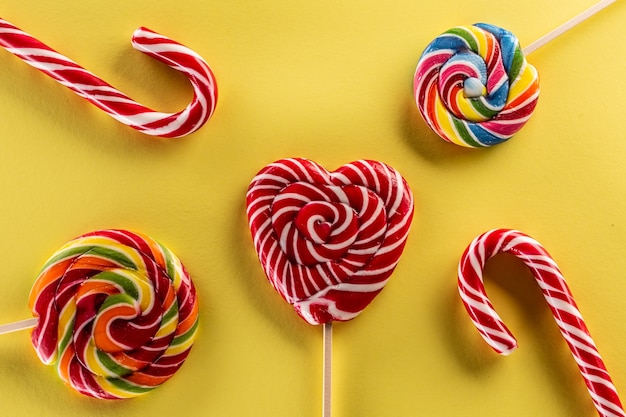 A tasty set of sweet candies like lollipops with rainbow colour and yellow background.