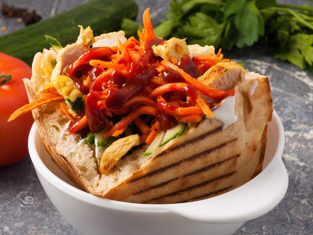 Tasty Shawarma with chicken in a pit with carrots and ketchup.