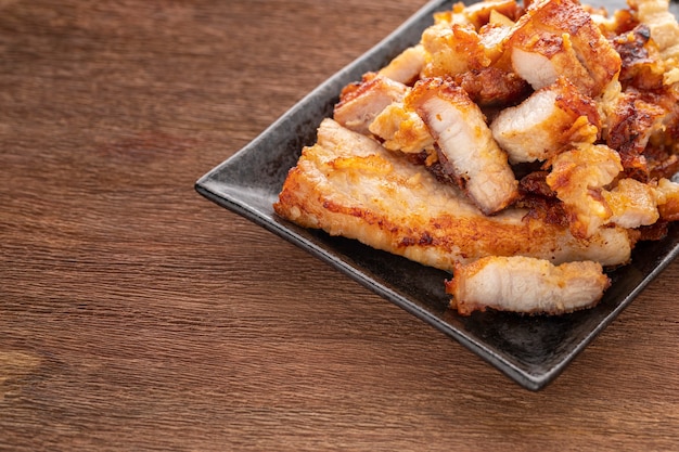 Tasty slice fried pork in rectangular ceramic plate on rustic natural wood texture background