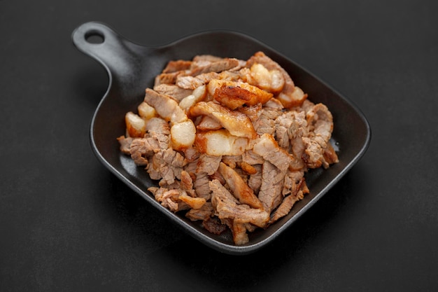 Foto gustosa carne di filetto di manzo alla griglia affettata in padella nera su sfondo texture tono scuro