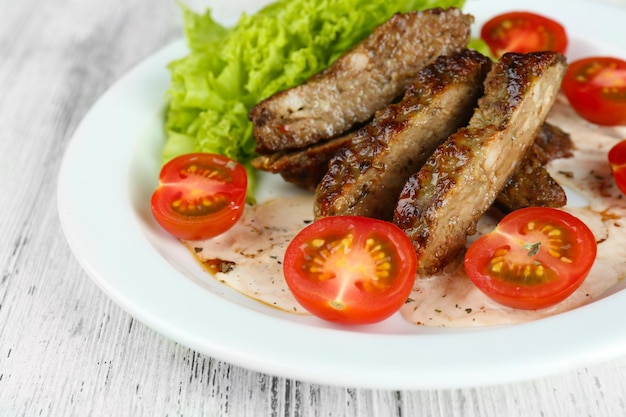 Tasty slices of meat with sauce and cherry tomato on table close up