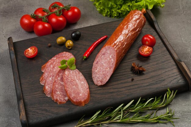 Photo tasty smoked sausage servelat or salami on a dark wooden background