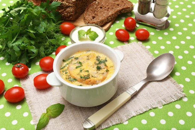 Tasty soup in saucepan on tablecloth close up