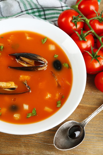 Foto gustosa zuppa di cozze pomodori e olive nere in una ciotola su fondo di legno