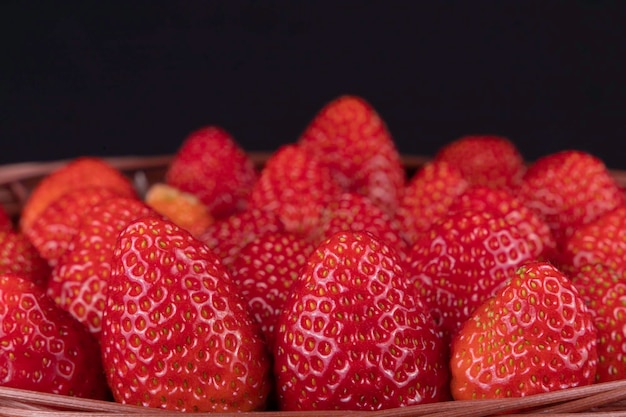 Tasty strawberries inside basket on black background Selective focus