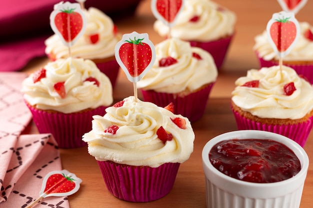 Tasty strawberry cupcakes on a wooden table