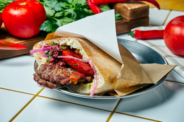 Gustoso cibo di strada - pita con pomodoro, cipolla e salsa, hamburger di manzo su un tavolo bianco. cucina greca. visualizza.
