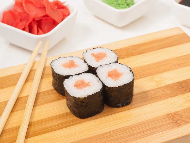 Tasty sushi roll with salmon in nori seaweed on a wooden board