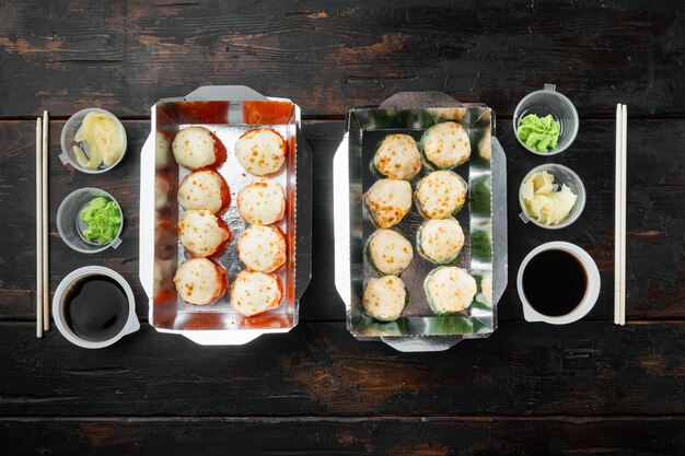 Tasty sushi rolls in disposable boxes set, on old dark  wooden table