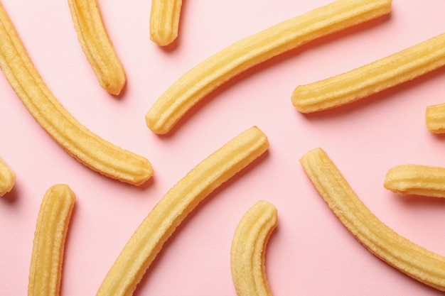 Tasty sweet churros on pink background