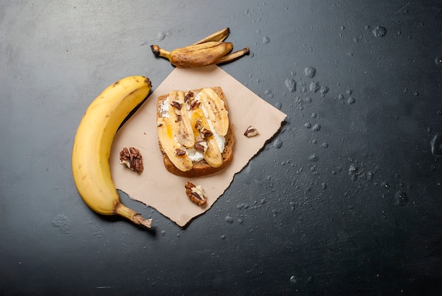 Tasty sweet sandwiches with bananas, nuts and chocolate,  on black table 