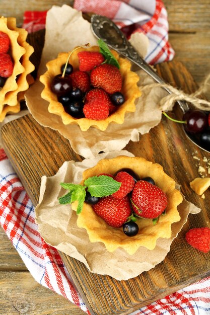 Tasty tartlets with berries on wooden table