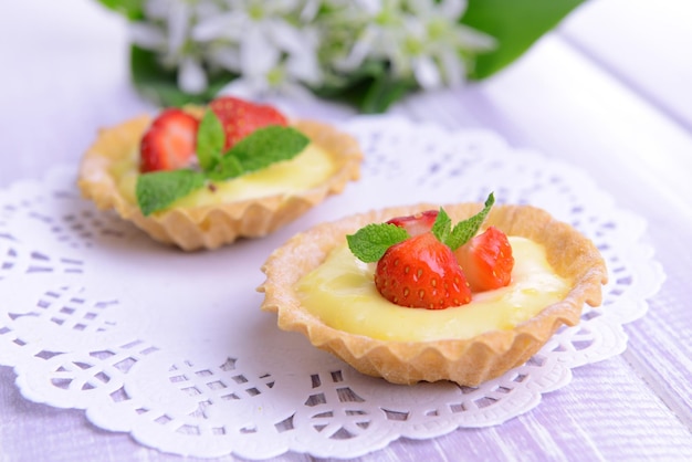 Tasty tartlets with strawberries on table closeup