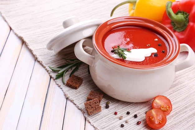 Tasty tomato soup and vegetables on wooden table