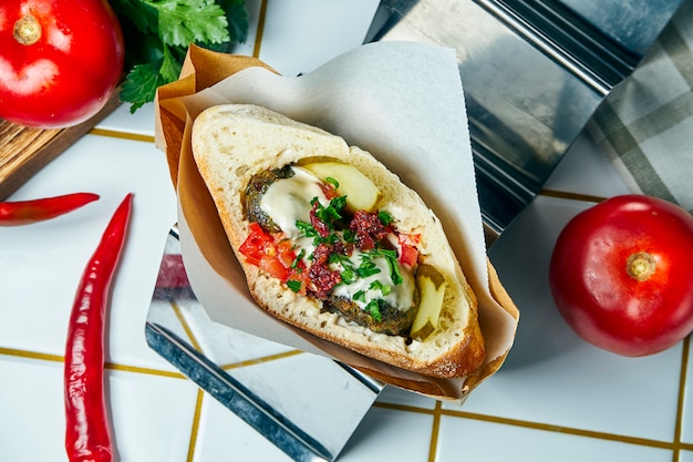 Gustoso cibo vegano di strada - pita con falafel, cipolla e salsa, su un tavolo bianco. cucina greca. visualizza.