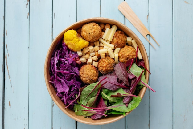 Gustosa insalata vegetariana vegana con ceci, falafel e foglie servite su piatto.