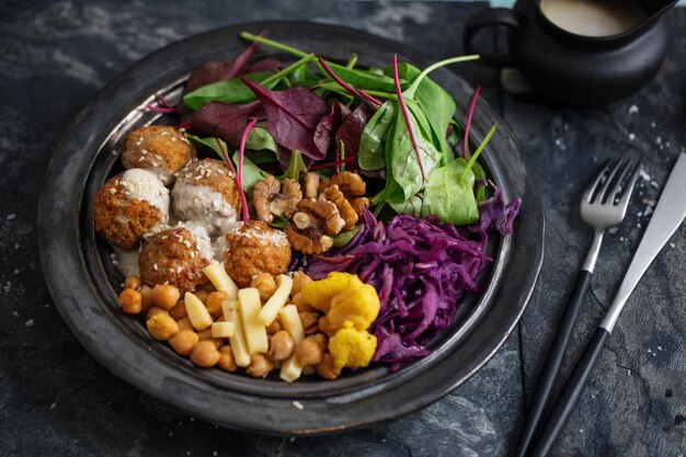 Gustosa insalata vegetariana vegana con ceci, falafel e foglie servite su piatto.