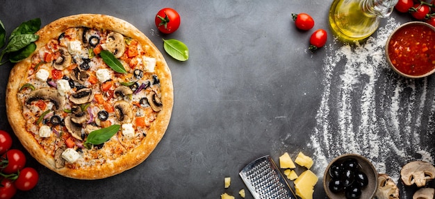 Tasty vegetable pizza and cooking ingredients tomatoes and basil on black background top view