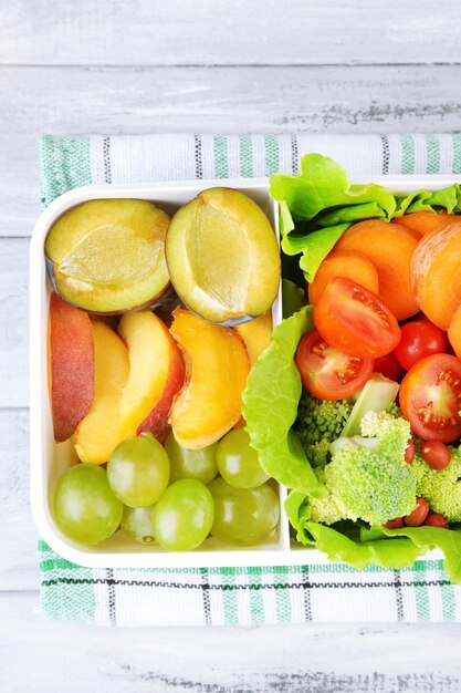 Tasty vegetarian food in plastic box on wooden table