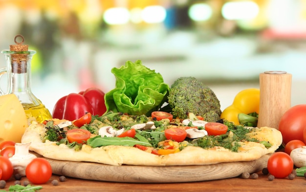 Tasty vegetarian pizza and vegetables on wooden table