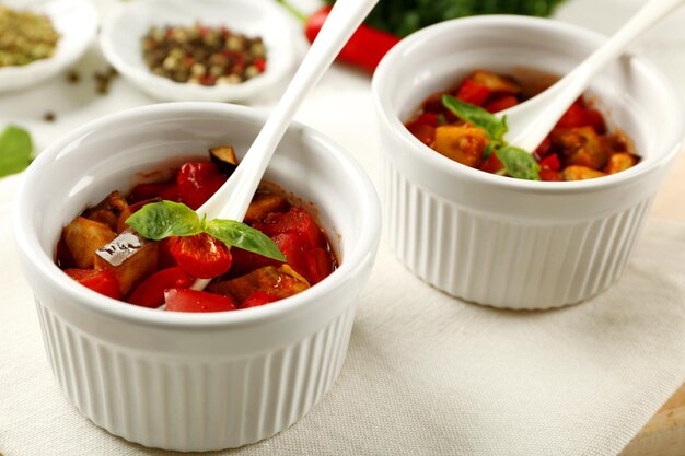 Вкусный вегетарианский рататуй из баклажанов, тыквенных помидоров в мисках на фоне деревянного стола