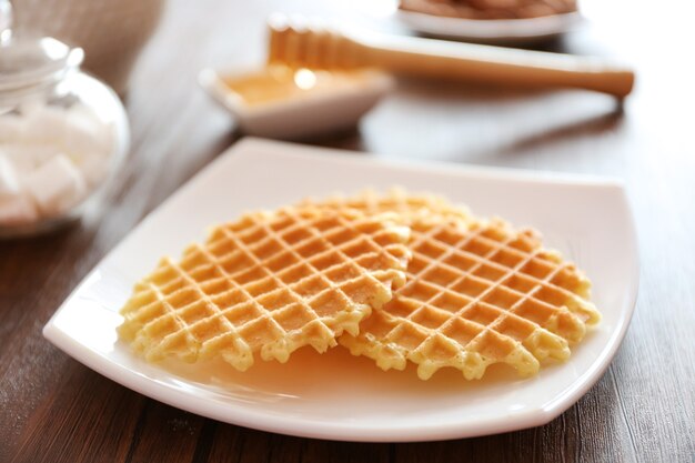 Tasty waffles with honey on plate