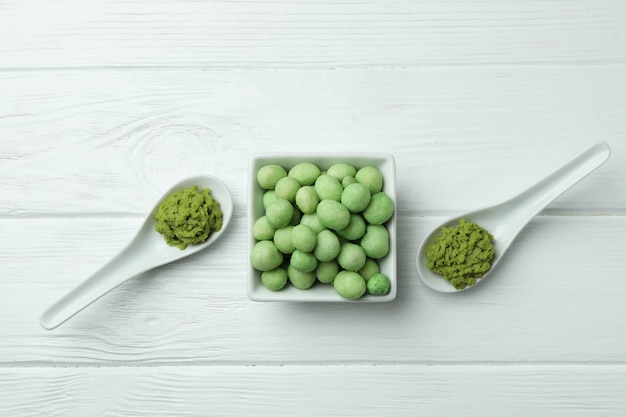 Tasty wasabi nuts and sauce on white wooden