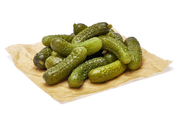 Tasty whole green cornichons on parchment paper isolated on a white background