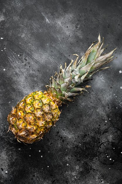 Tasty whole pineapple on black dark stone table background top view flat lay with copy space for text