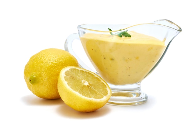 Tasty yellow hollandaise sauce in glass bowl gravy boat isolated on white background