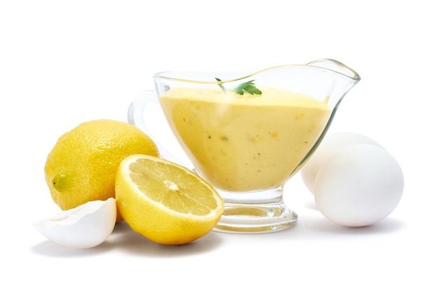 Tasty yellow hollandaise sauce in glass bowl gravy boat isolated on white background