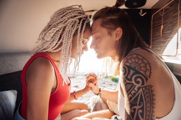 Tatoeage bij de hand. Blondharige knappe man met tatoeage op zijn hand met de hand van zijn schattige vriendin