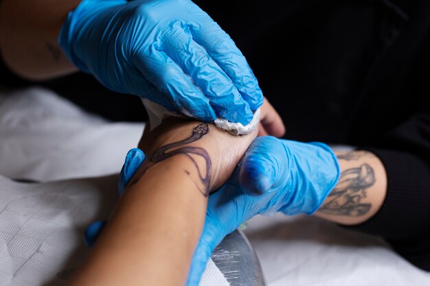 Foto tatoeëerder die handschoenen draagt hoge hoek