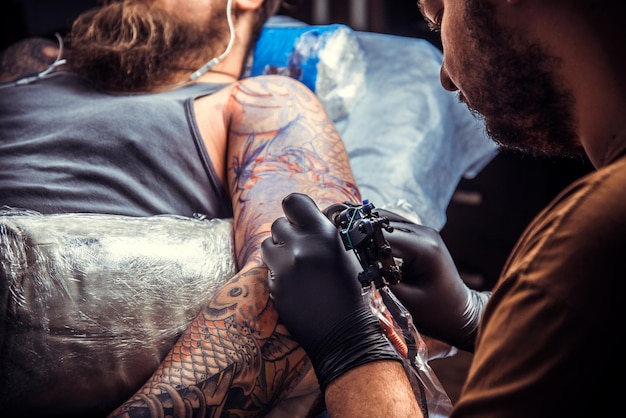 Tatoeëerder die het proces van het maken van een tatoeage in een tatoeagesalon laat zien