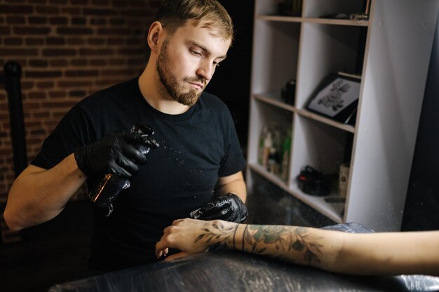 Tatoeëerder hydrateert de hand door deze te steriliseren met water uit een spuitfles