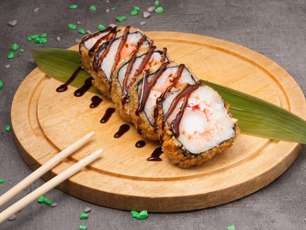 Tatsy tempura shrimp roll on a banana leaf on a wooden board