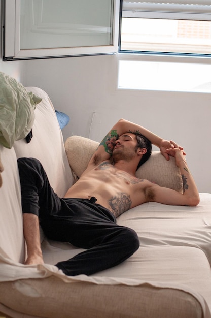 ソファで昼寝をしている刺青の若い男