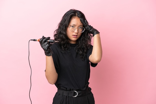 Tattoo artist asian woman isolated on pink background with surprise expression