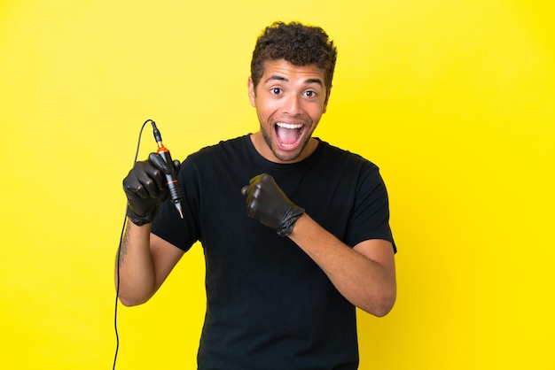 Tattoo artist Brazilian man isolated on yellow background celebrating a victory