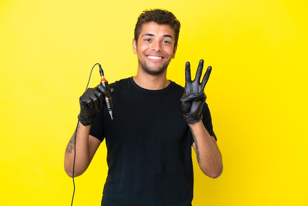 Tattoo artist Brazilian man isolated on yellow background happy and counting three with fingers