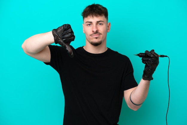 Tattoo artist caucasian man isolated on blue background showing thumb down with negative expression