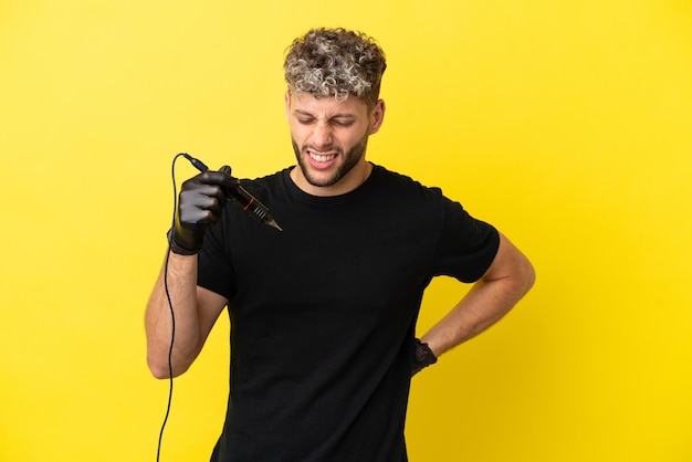 Tattoo artist caucasian man isolated on yellow background suffering from backache for having made an effort