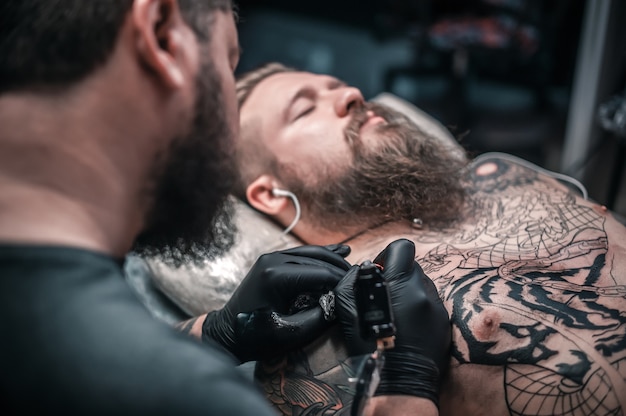 Tattoo artist demonstrates the process of getting tattoo in salon