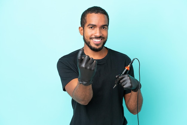 Tattoo artist Ecuadorian man isolated on blue background doing coming gesture