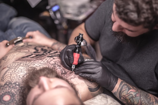 Tattoo artist makes a tattoo on the skin in studio